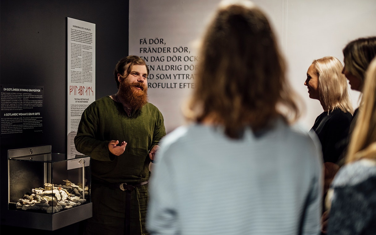 Tour guide explaining Viking artifacts at Stockholm museum exhibit.