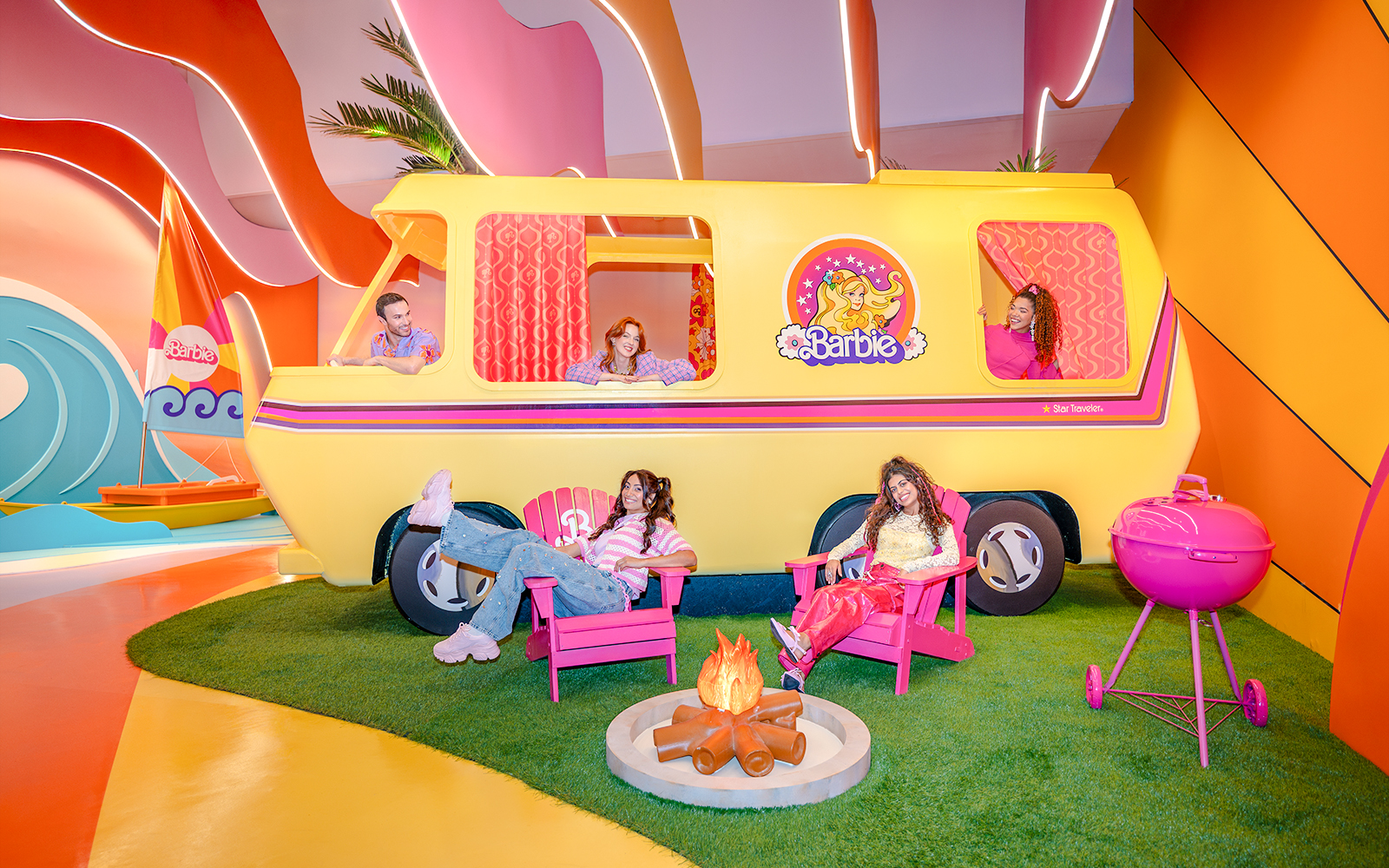 Barbie Malibu van with people relaxing in chairs and a campfire nearby.