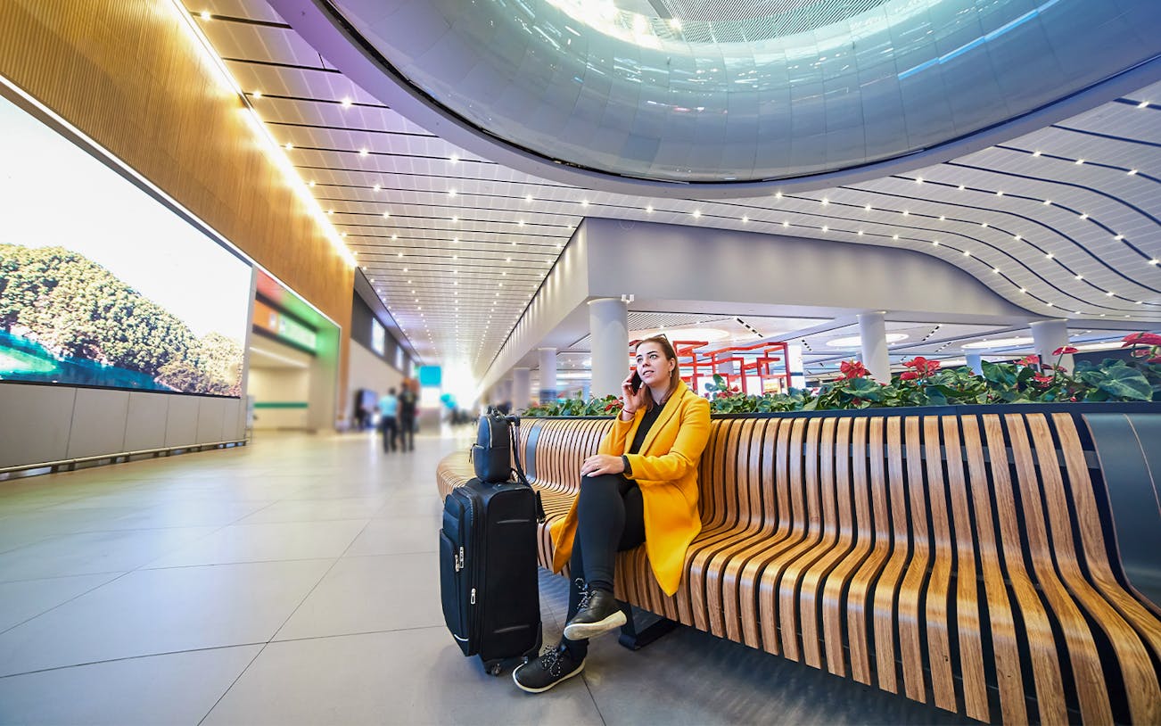 Traveler seated with luggage at New Istanbul Airport terminal.
