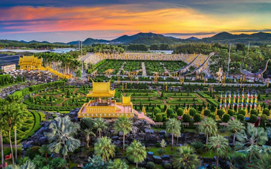 Nong Nooch Tropical Garden with intricate landscaping and dinosaur sculptures at sunset, Pattaya, Thailand.