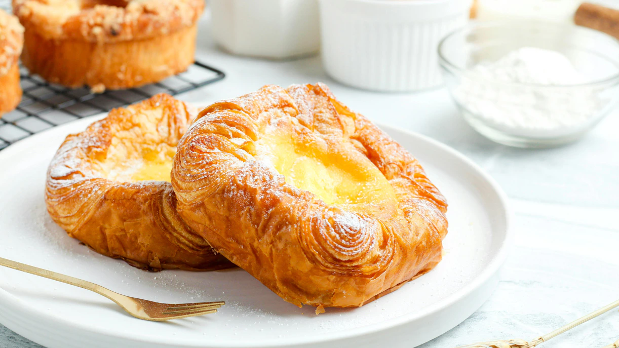 Danish pastry with icing sugar on a white plate.
