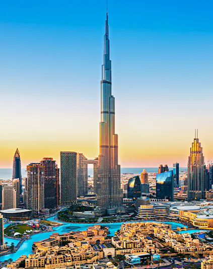 Burj Khalifa towering over Dubai downtown skyline at sunset.
