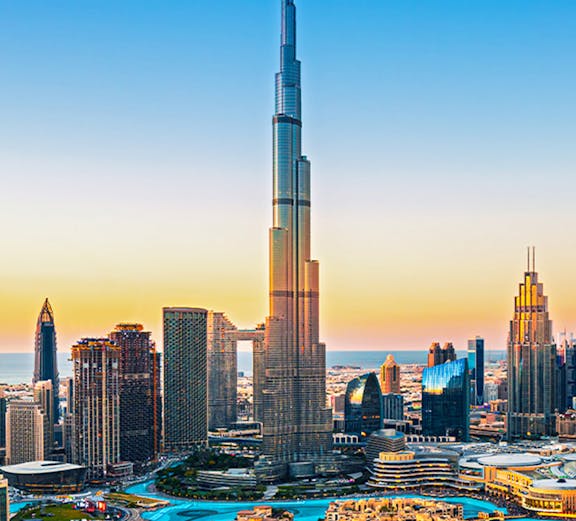 Burj Khalifa towering over Dubai downtown skyline at sunset.