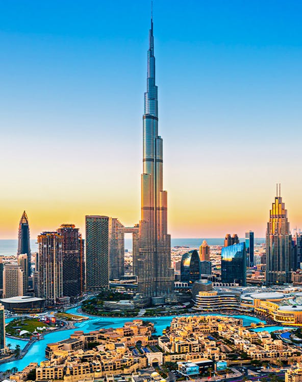 Burj Khalifa towering over Dubai downtown skyline at sunset.