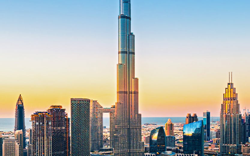 Burj Khalifa towering over Dubai downtown skyline at sunset.