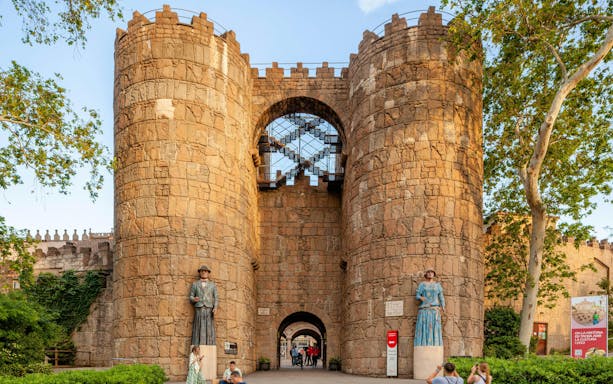 Entrance to Poble Espanyol with stone towers and statues in Barcelona, Spain.