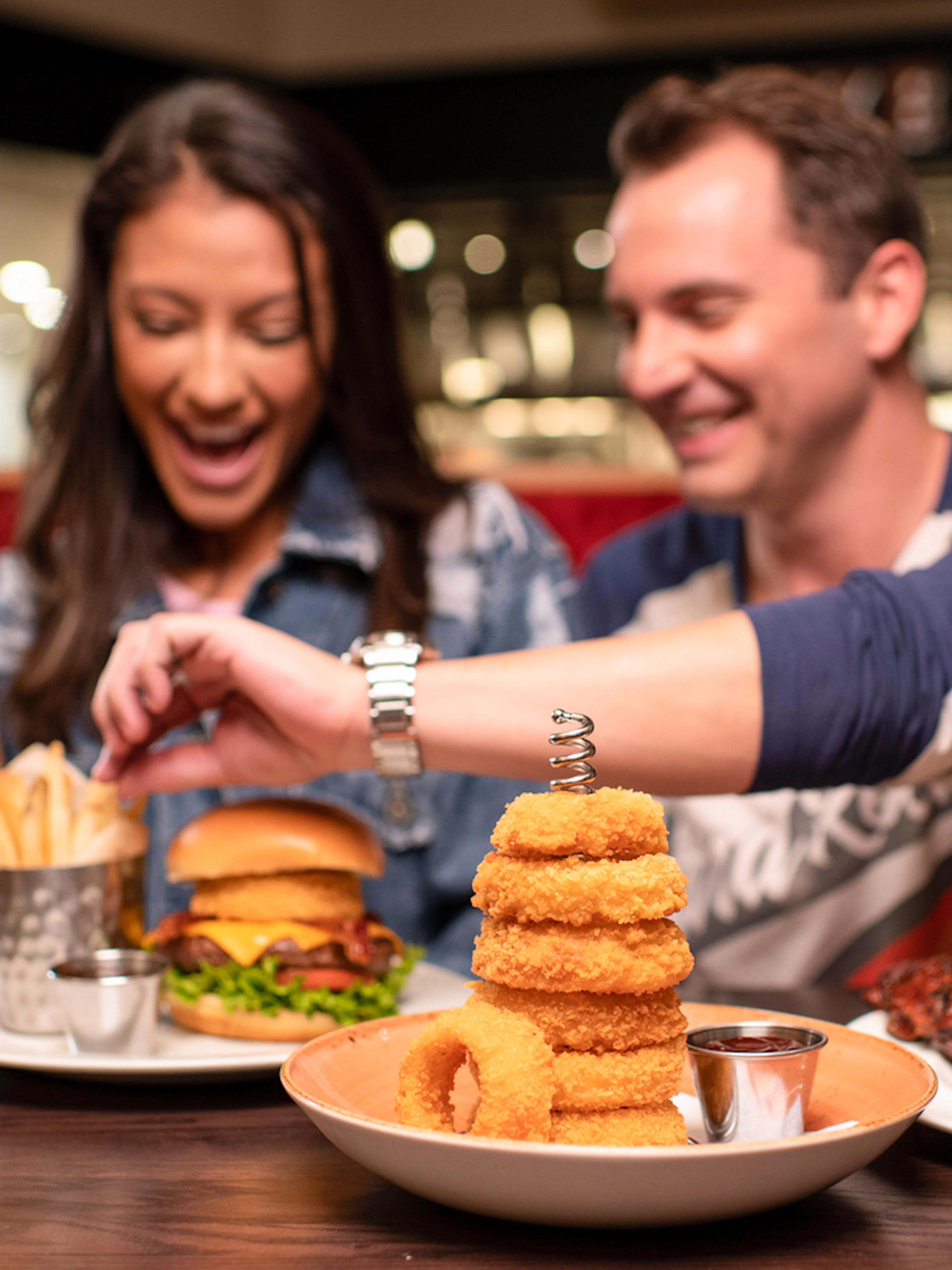 Couple dining with burgers and drinks at Hard Rock Cafe, Milan.