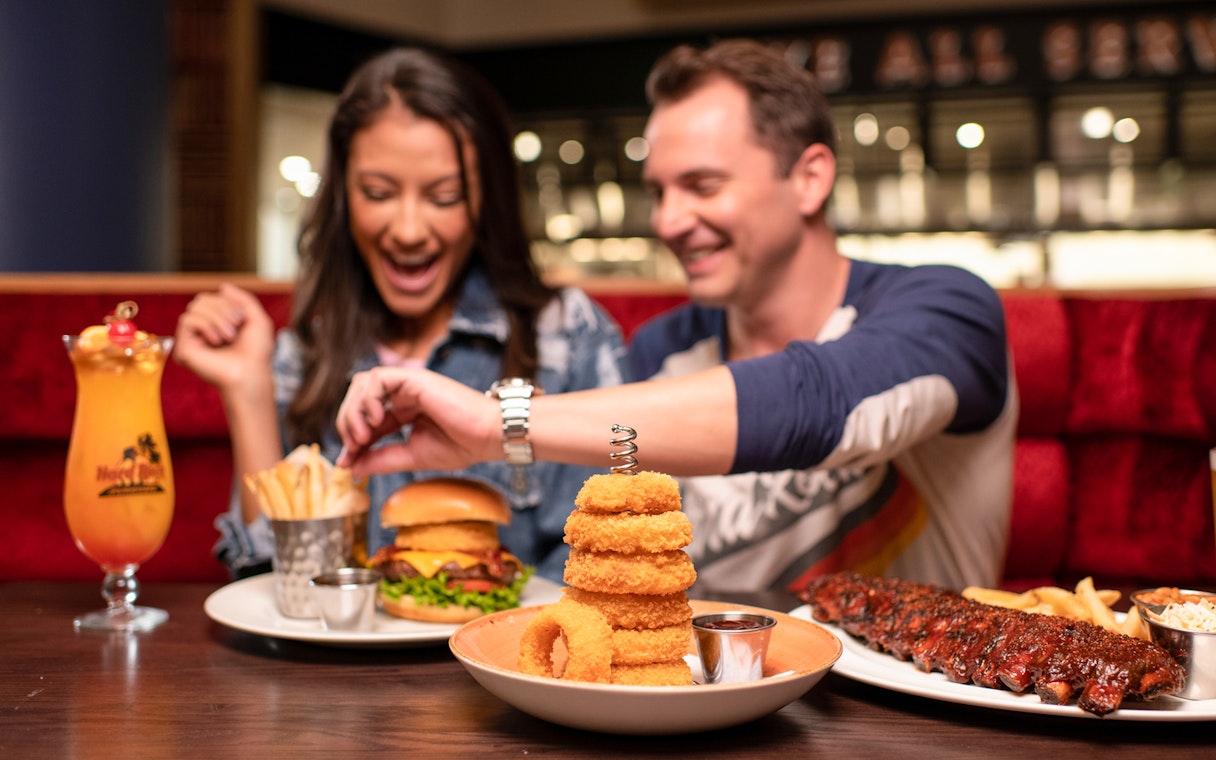 Couple dining with burgers and drinks at Hard Rock Cafe, Milan.