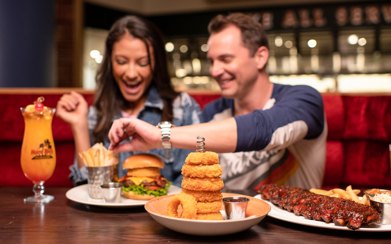 Couple dining with burgers and drinks at Hard Rock Cafe, Milan.