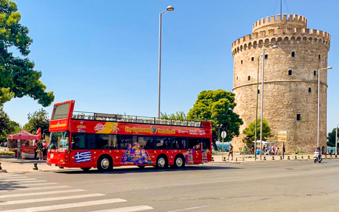 Red double-decker bus near the White Tower on Thessaloniki Hop-On-Hop-Off Tour.