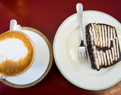 Coffee cup and chocolate cake slice on a table.