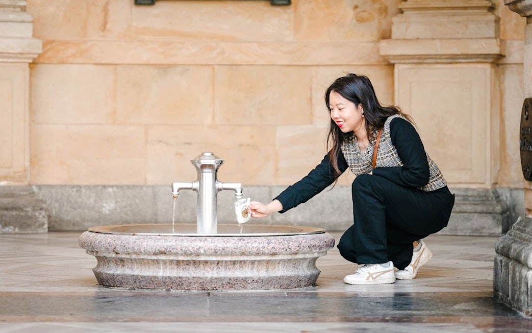 Person collecting water from mineral spring in Karlovy Vary.