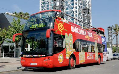 Barcelona tour bus parked near modern architecture on a sunny day.