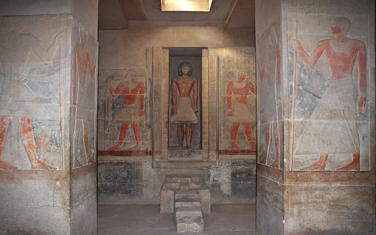 Ancient Egyptian frescoes and statue in Saqqara necropolis, Egypt.