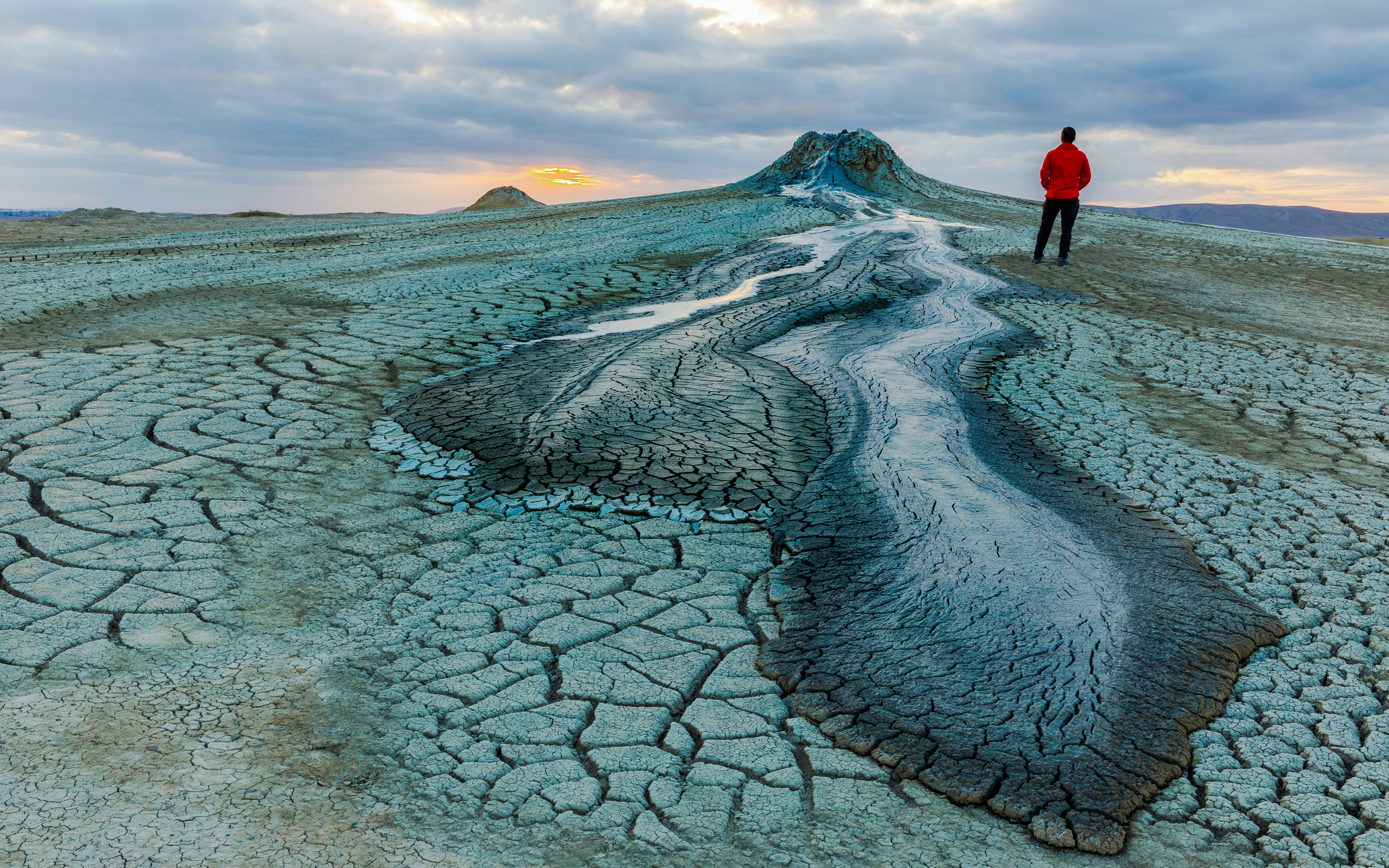 Mud volcanoes in Gobustan with a person standing at sunset.