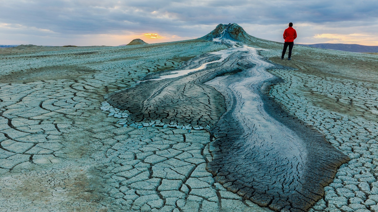 Mud volcanoes in Gobustan with a person standing at sunset.