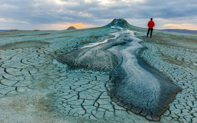 Mud volcanoes in Gobustan with a person standing at sunset.