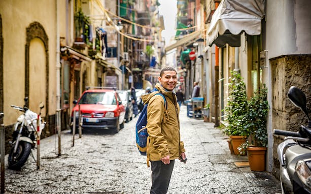 Traveler exploring a narrow street in Naples, Italy.