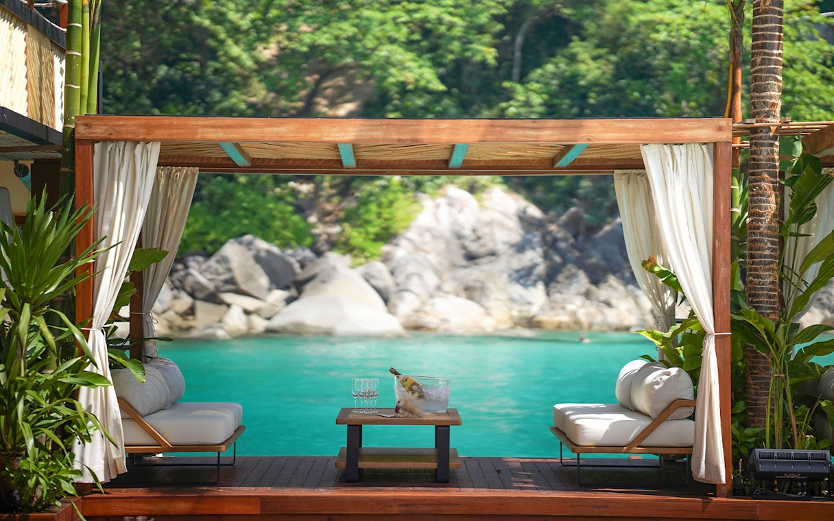 Private cabana at Yona Beach Club, Phuket, overlooking turquoise water and lush greenery.