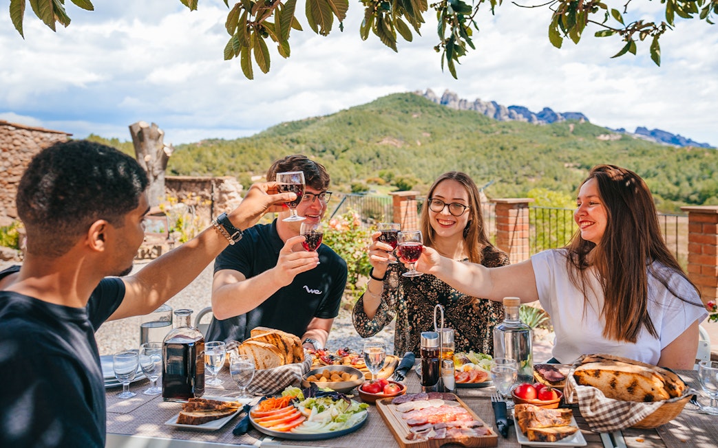 Tourists toasting with wine at Montserrat Monastery lunch table.