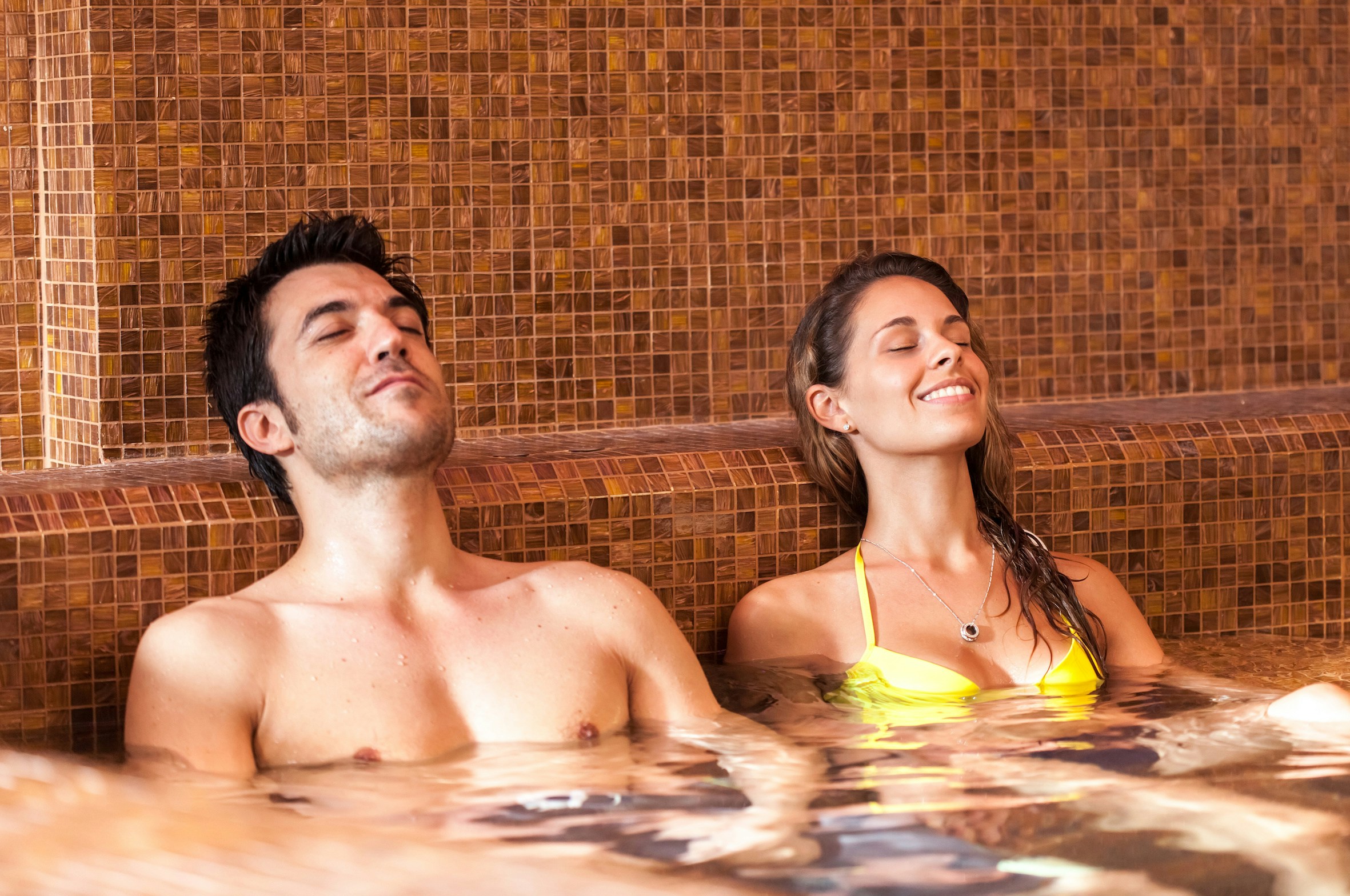 Couple relaxing in a thermal bath with tiled walls.