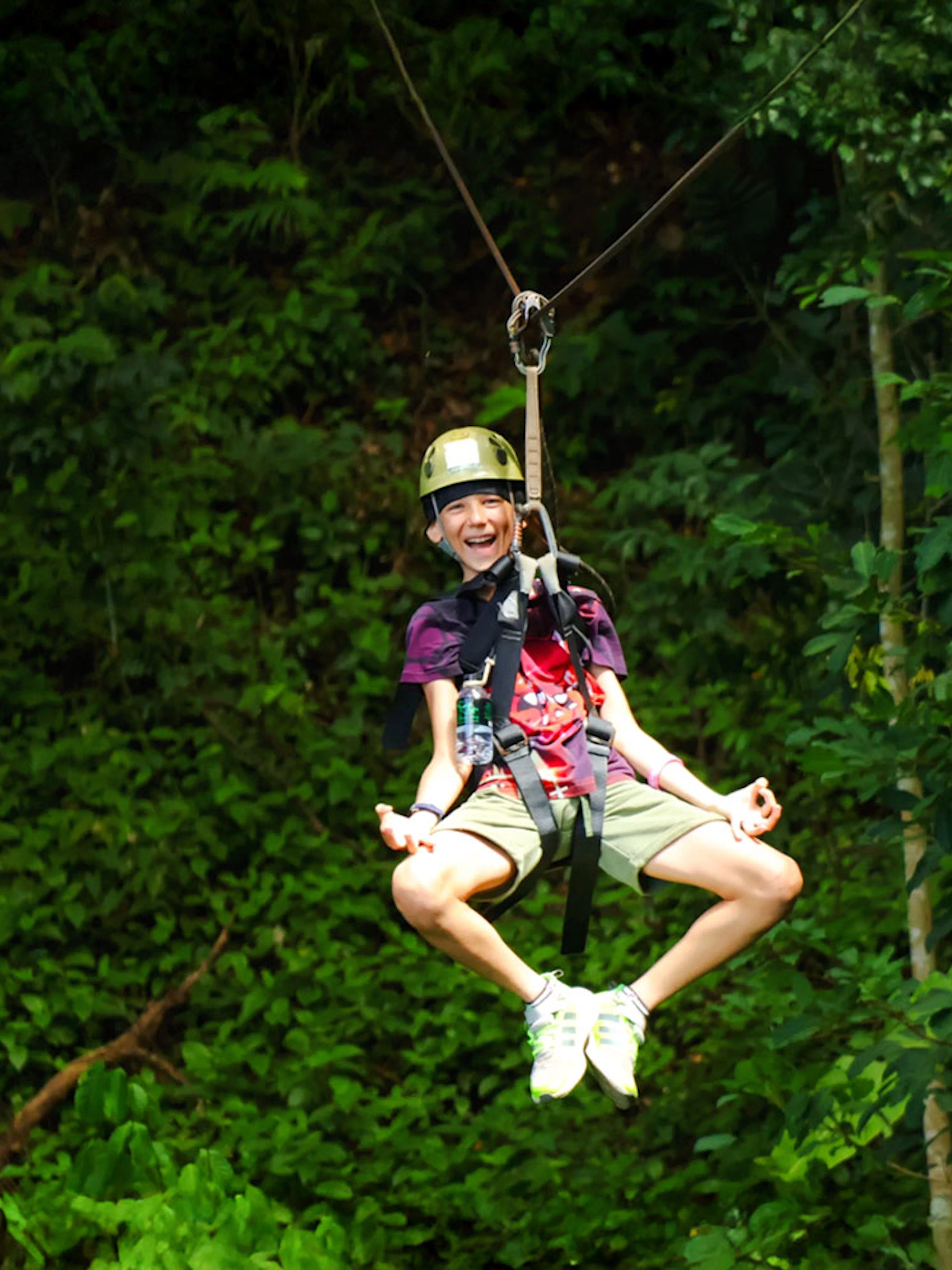 Person ziplining through lush forest at Flying Hanuman, Phuket.