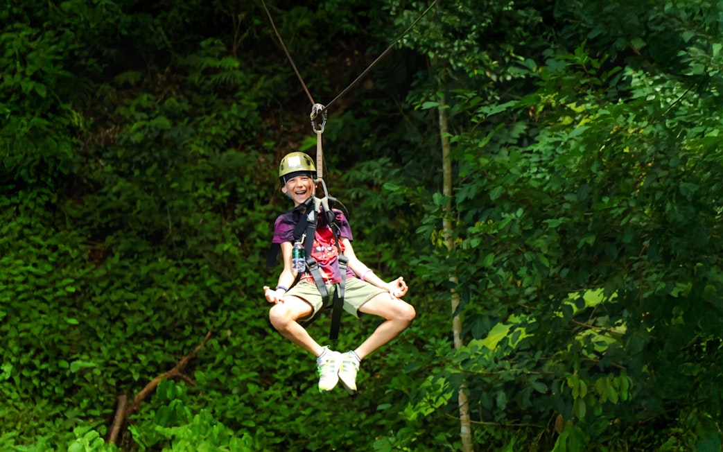 Person ziplining through lush forest at Flying Hanuman, Phuket.