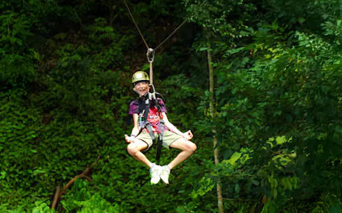 Person ziplining through lush forest at Flying Hanuman, Phuket.