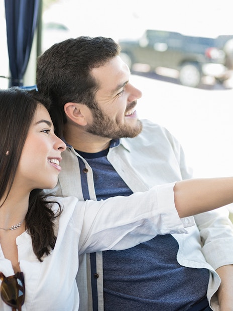 Couple smiling and pointing out the window on a bus tour.