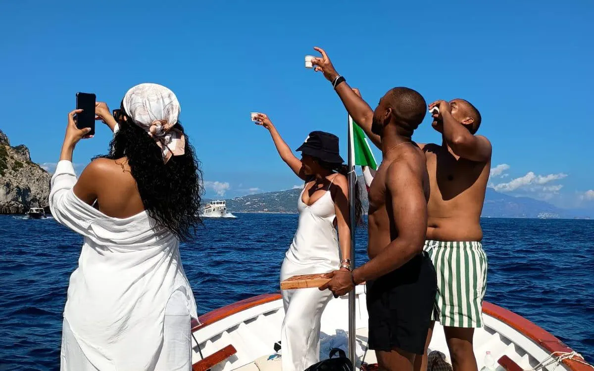 Boat tour in Capri with people enjoying local snacks and homemade limoncello.