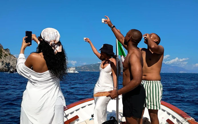 Boat tour in Capri with people enjoying local snacks and homemade limoncello.