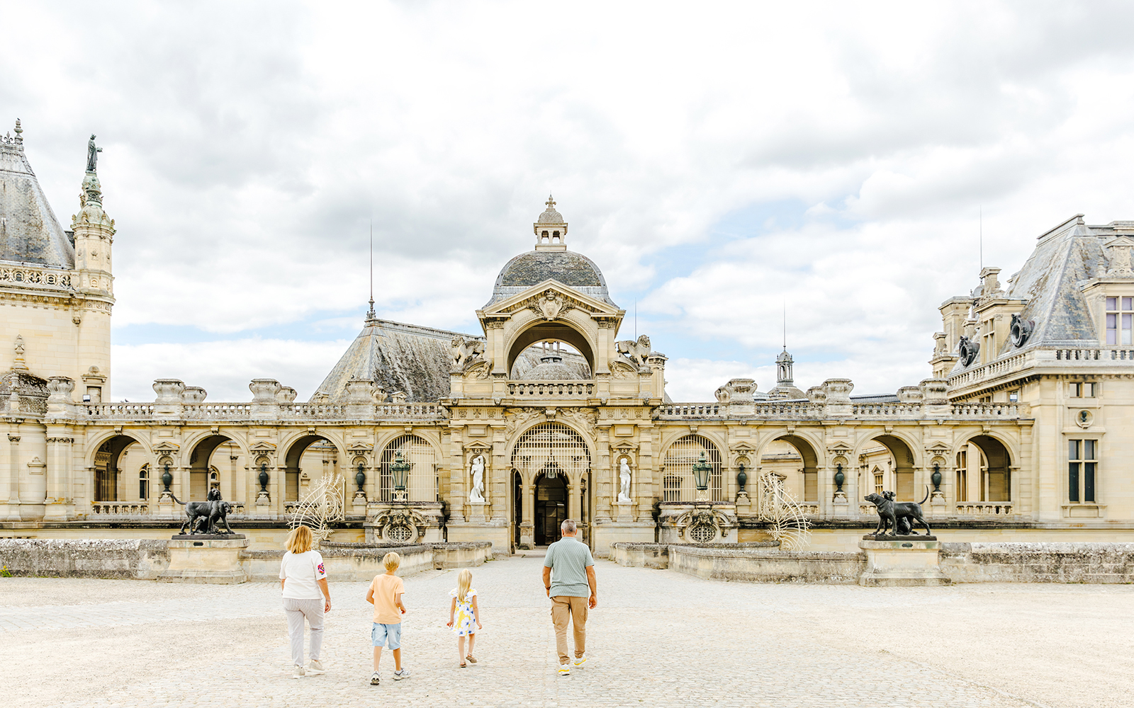 Visitors walking towards the entrance of Chateau of Chantilly, France.
