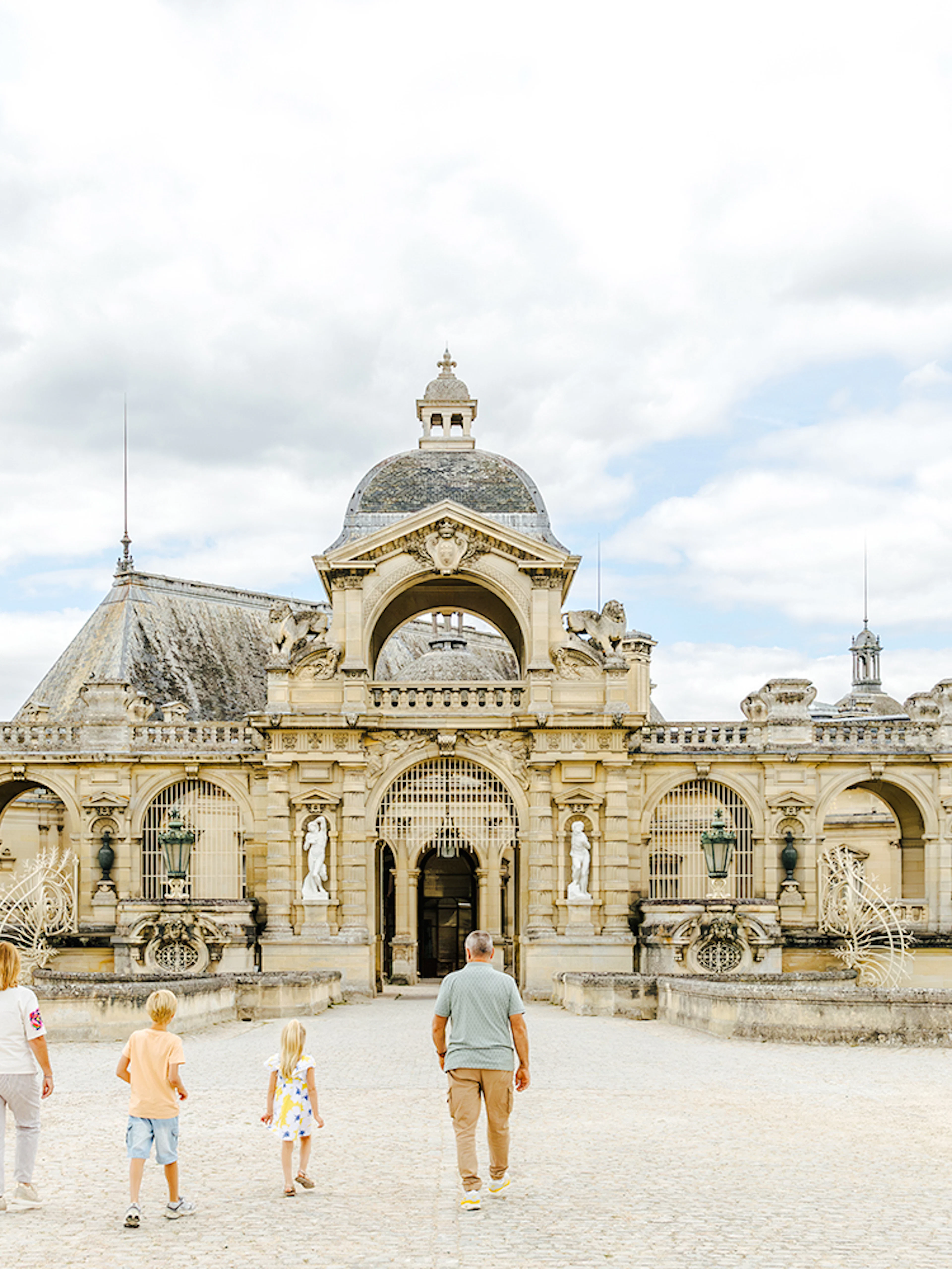 Visitors walking towards the entrance of Chateau of Chantilly, France.