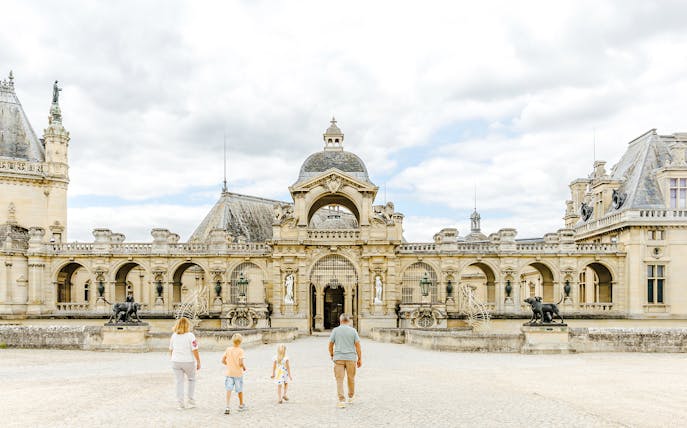 Visitors walking towards the entrance of Chateau of Chantilly, France.