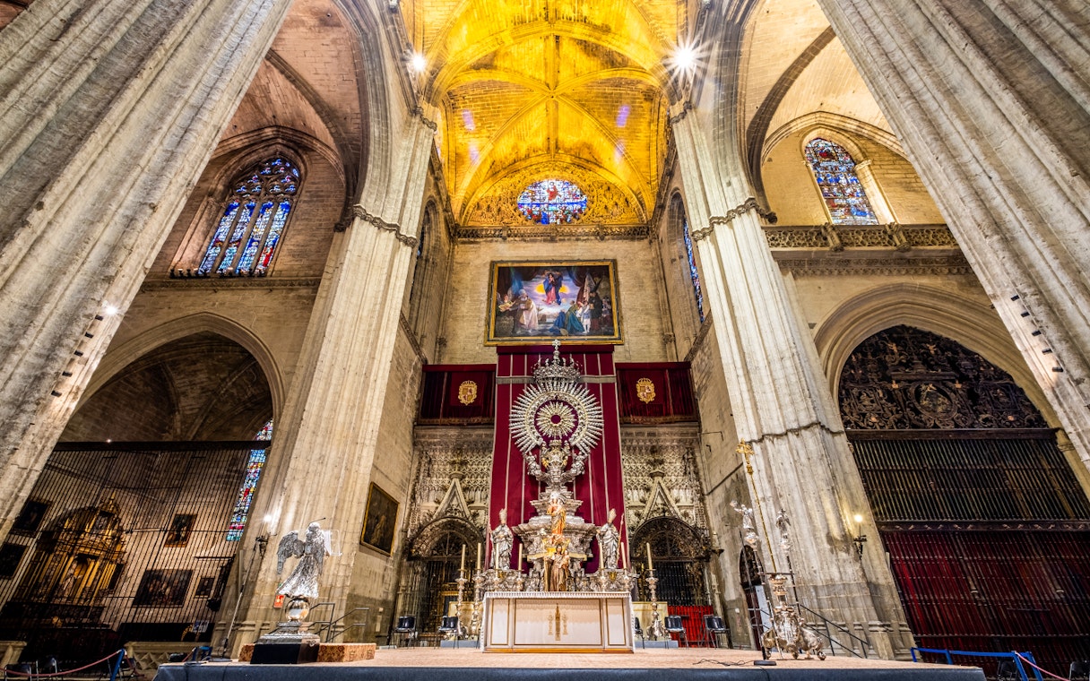 Interior of Seville Cathedral with ornate altar and stained glass windows, part of Exclusive Cathedral & Giralda Tour.