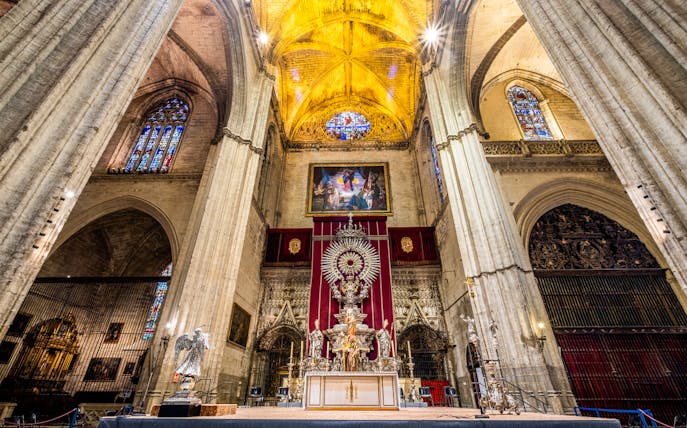 Interior of Seville Cathedral with ornate altar and stained glass windows, part of Exclusive Cathedral & Giralda Tour.