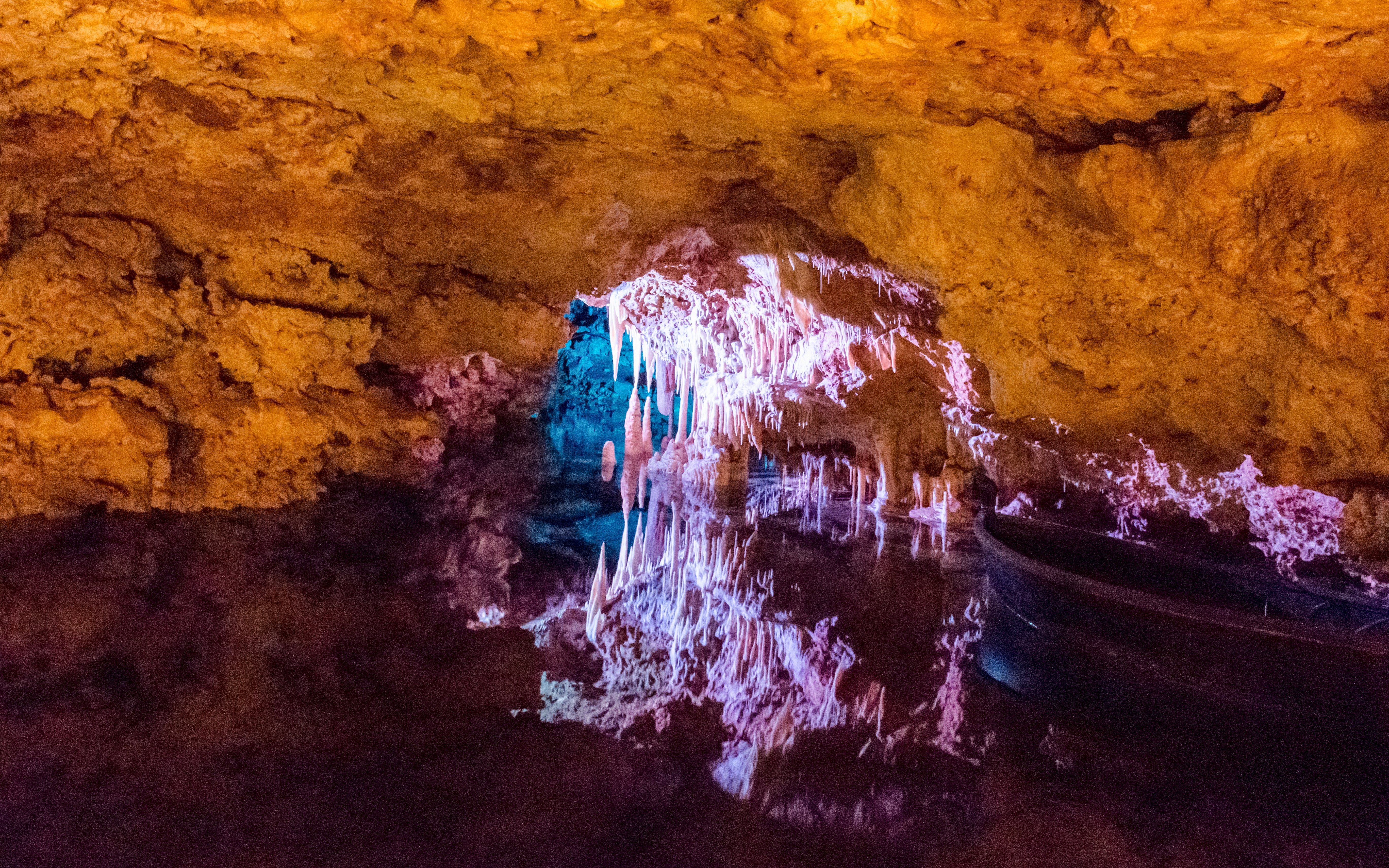 Stalactites illuminated in Hams' Caves, Mallorca, reflecting in underground lake.