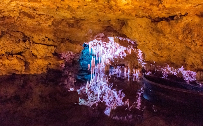 Stalactites illuminated in Hams' Caves, Mallorca, reflecting in underground lake.