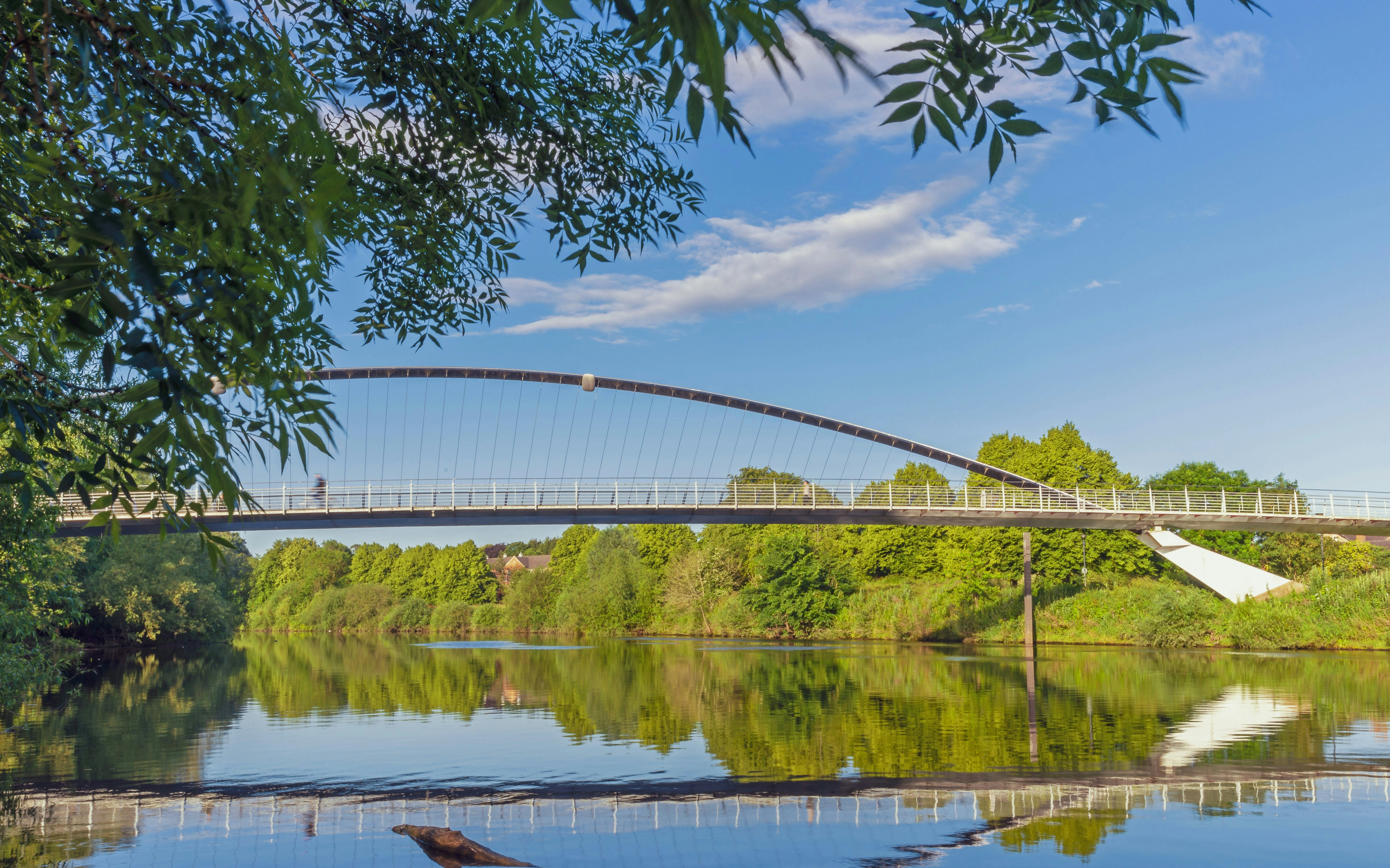 Millennium Bridge spanning the River Ouse in York, surrounded by lush greenery.