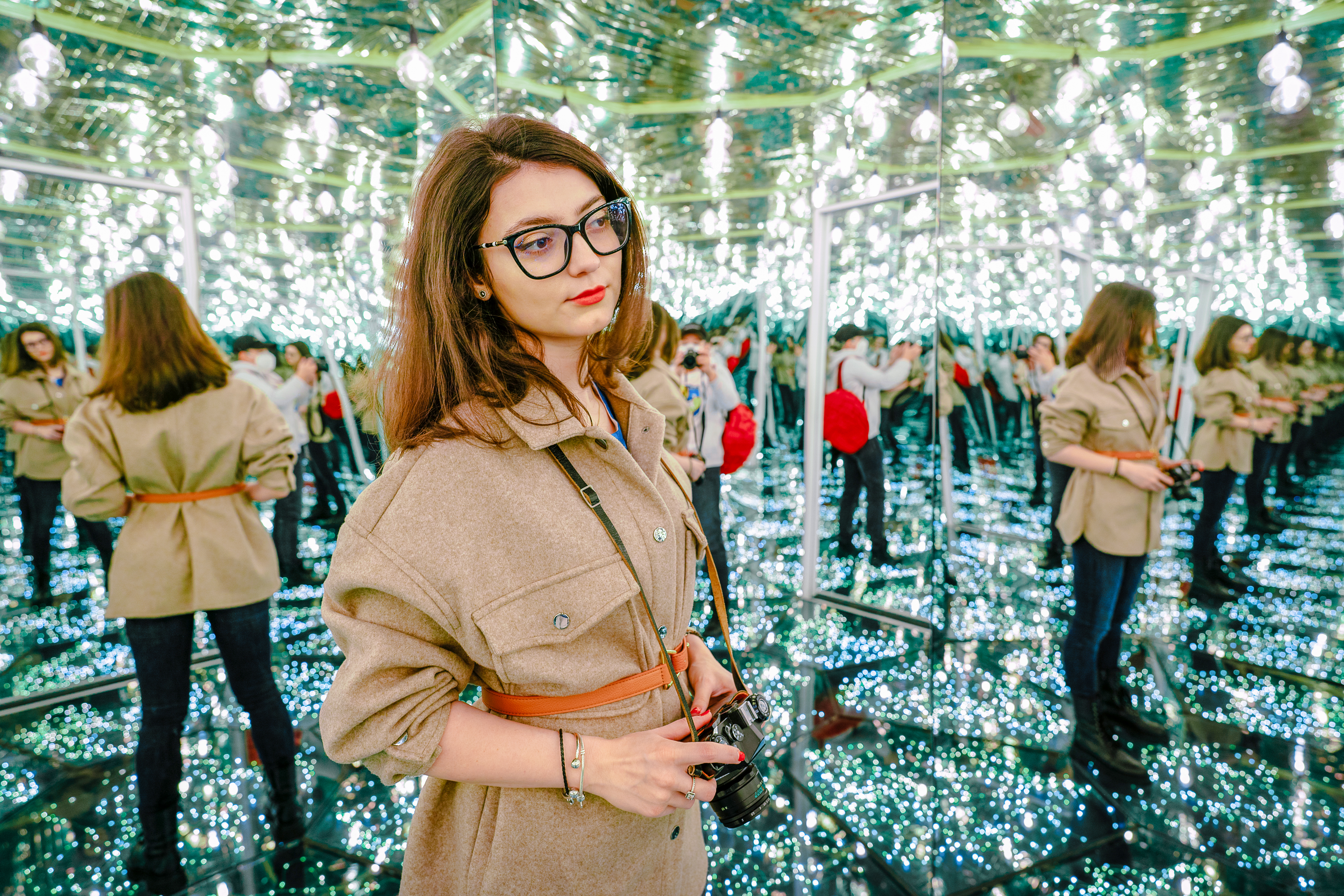 Woman exploring a mirror labyrinth with reflections and lights.