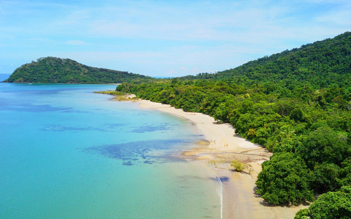 Queensland beach with lush greenery and clear blue water on Half-Day Waterfall Wanderers Tour.