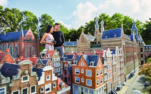 Visitors exploring miniature Dutch buildings at Madurodam park.