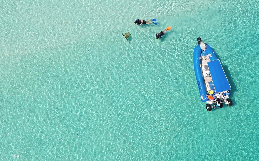 Snorkelers and a boat in clear waters during a K'gari (Fraser Island) tour.