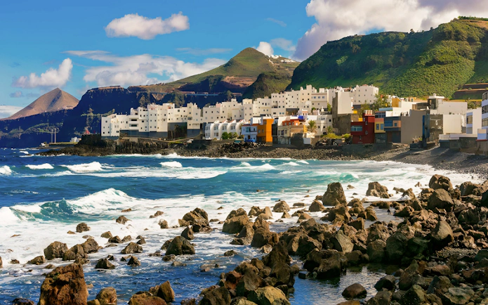 Coastal view of El Roque en El Pagador de Moya, Gran Canaria, Spain, with ocean waves and rocky shore.