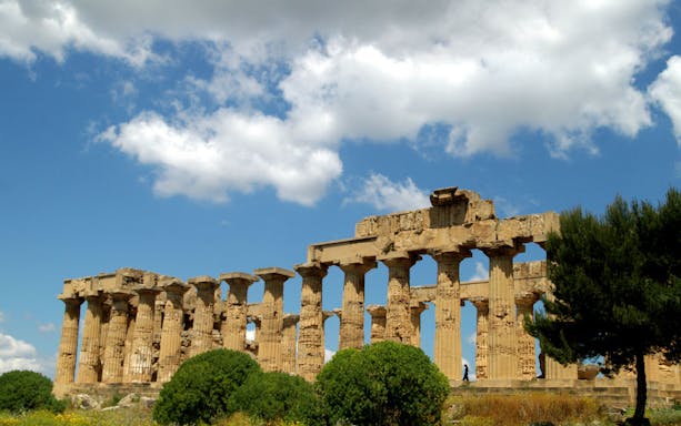 Ancient Greek temple ruins in Agrigento, Sicily under a blue sky.