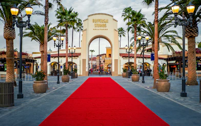 Universal Studios Hollywood entrance with red carpet and palm trees.