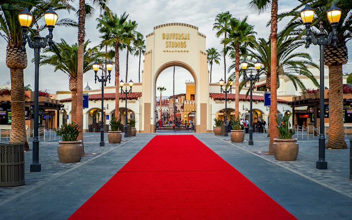 Universal Studios Hollywood entrance with red carpet and palm trees.