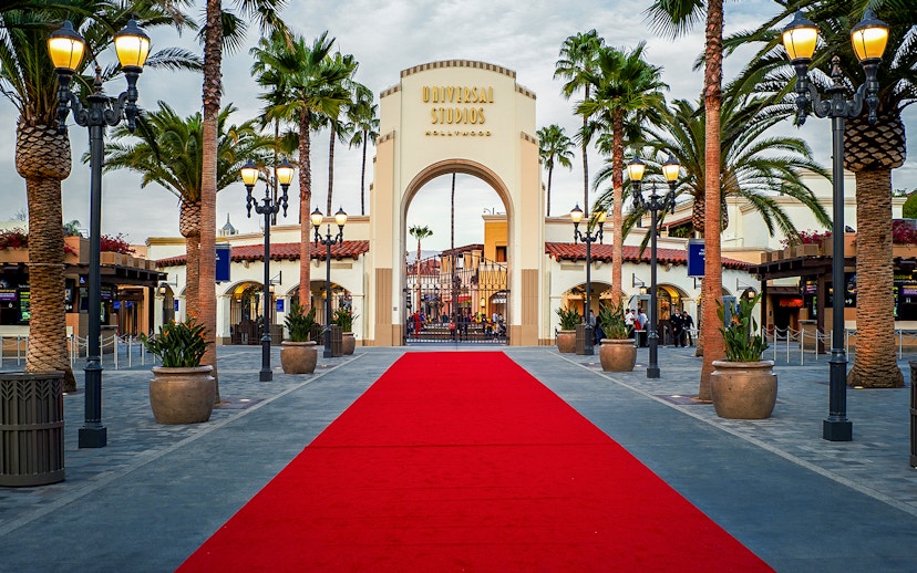 Universal Studios Hollywood entrance with red carpet and palm trees.
