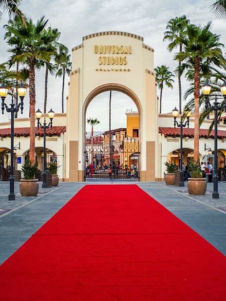 Universal Studios Hollywood entrance with red carpet and palm trees.