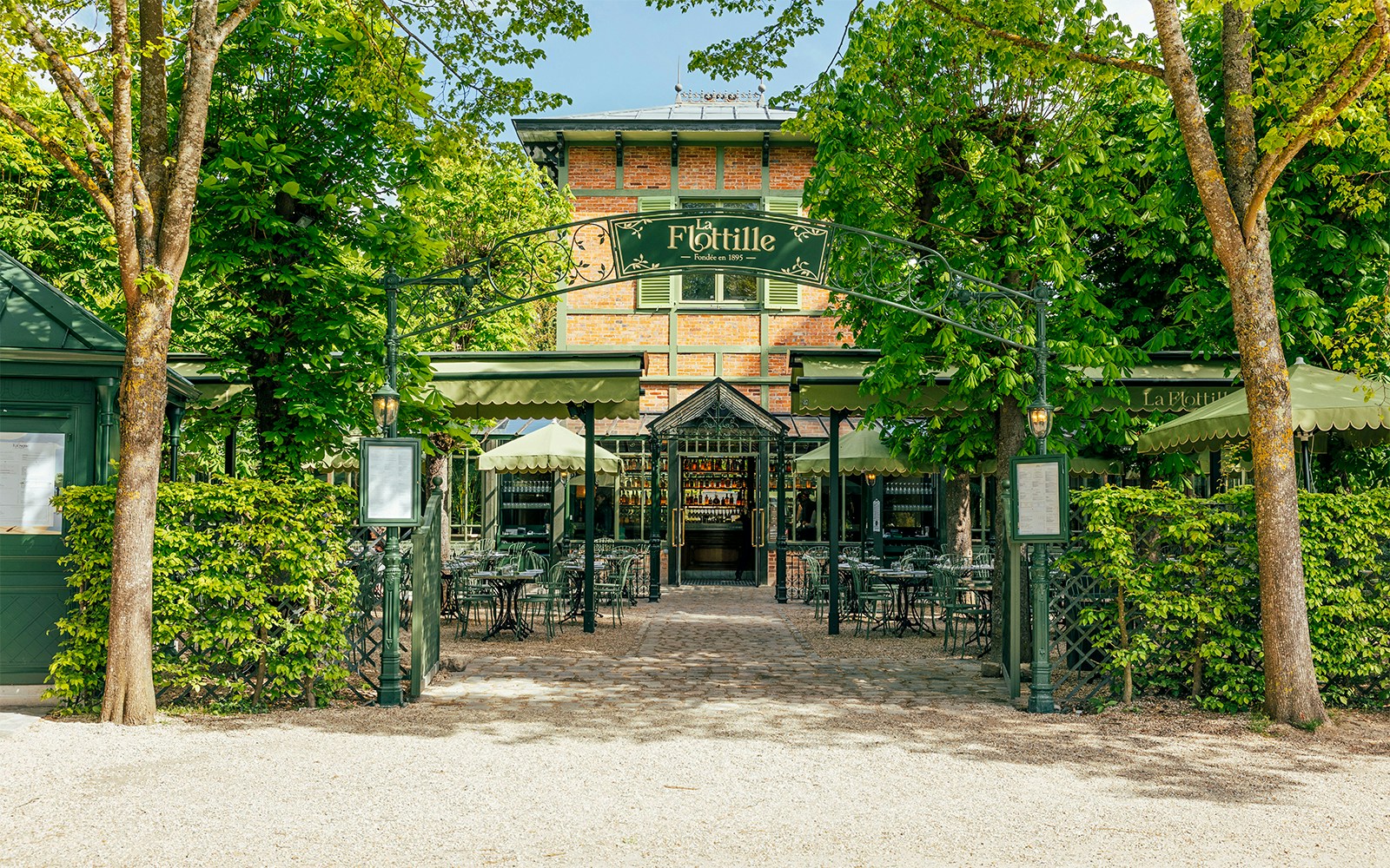Flottille café entrance with outdoor seating in a lush garden setting.